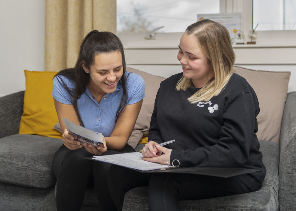 Support worker helping a parent of someone affected by Cystic Fibrosis to complete a form.