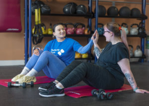 Volunteer doing exercises with a client in the gym as part of one-to-one support.