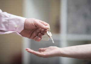 A set of house keys being passed from one hand to another.